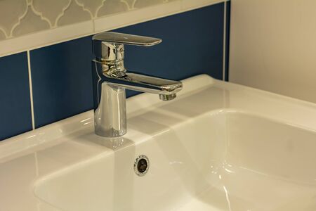 Photo of the interior of the bathroom. Chrome modern tap and ceramic white sink. Close-up, modern...