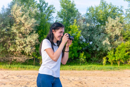 Professional photographer woman at work. Taking pictures outdoors in the park. The brunette looks at...