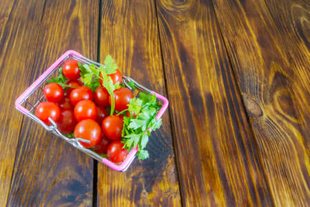 Cherry tomatoes in a basket on a dark wooden table. Copy space, selective focus.の写真素材