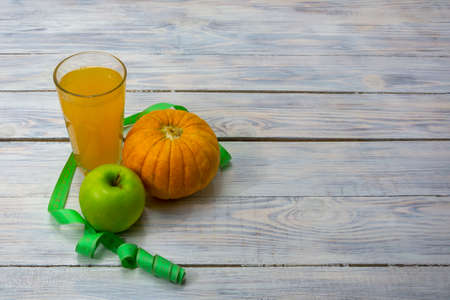 Glass cup of fresh apple and pumpkin juice on wooden table. Slimming food. Detox diet, vegan food. Selective focus, copy space.の写真素材
