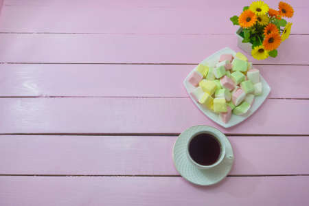 Morning breakfast, coffee and marshmallows on pink wooden background. Copy space. Tenderness...