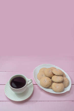 Cup of Americano coffee and homemade cookies on pink background. Copy space. The concept of romance, tenderness, coffee time.の写真素材
