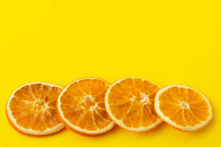 Dried orange slices on a bright yellow background. Close-up, place for your text, copy space.の写真素材