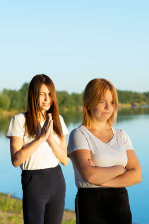 Two girls friends hold each other's hands for a walk near the river. Cropped view, rear view,...