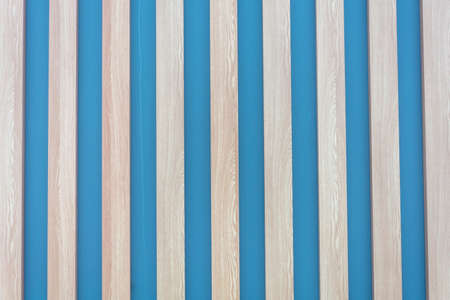 Wall is blue, covered on top with beams made of light natural wood. Stripes vertically, background for design and text, copy space.の写真素材