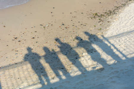 Shadows of people on sand near the sea. Concept of recollection, farewell to loved ones, departure...