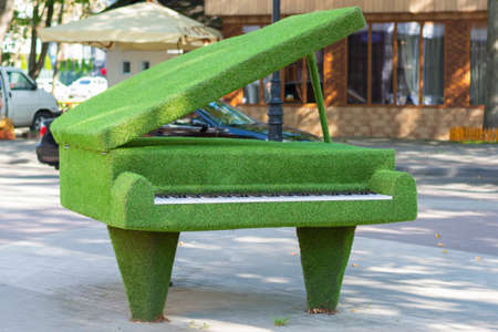Sculpture of a grand piano with an open lid made of artificial grass, urban topiary.の写真素材