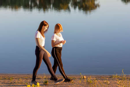 Two young friends are walking along the river bank. Friendship and love concept. Soft focus, blur.の写真素材