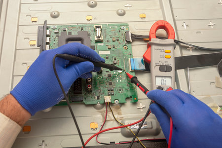 Volgograd, Russia - September, 2020: Diagnostics of printed circuit board TV. Hands hold the resistance test lead. Selective focus.のeditorial素材