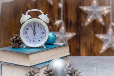 White alarm clock on stack of books in winter composition. New year concept. Selective focus, fog...