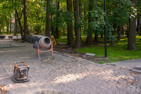 Repair of the sidewalk in city park. Concrete mixer and vibrating plate for laying paving slabs on...
