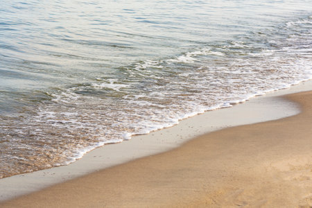 Soft wave with white foam on sandy seashore or ocean. Selective focus, fog view.