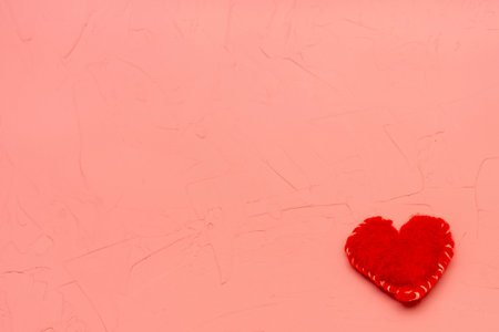 Red heart made of handmade wool on pink textured background. Copy space, place for your text. Valentine's day concept, love.の写真素材