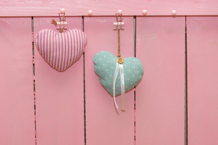 Two hearts made fabric against background of pink wooden wall made of boards. Concept for love of man and woman, Valentine's day, wedding. Copy space, place for your text.の写真素材
