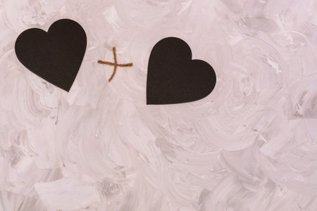 Heart plus heart together. Two black graphite hearts on gray textured background. Copy space for text. Concept for Valentine's day, lovers, wedding.の写真素材