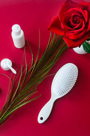 White hair brush and cosmetics on red velvet table with rose flower. Top view, selective focus.の写真素材