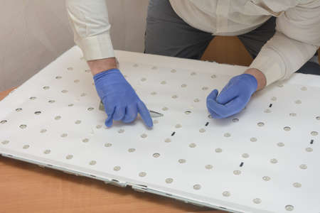 Disassembled panel of large LCD TV in service center. Technician removes LED lighting for repair....