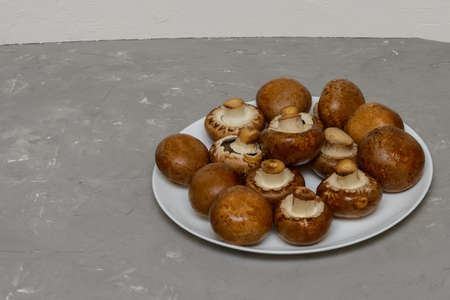 Royal large champignons on white plate. Fresh brown mushrooms for cooking. Gray concrete background.の写真素材