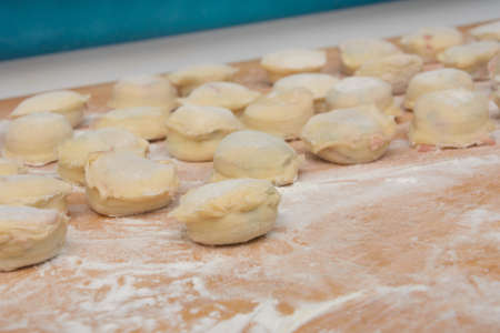 Homemade dumplings close-up on board with flour. Preparing ravioli for boiling. Close-up, selective...