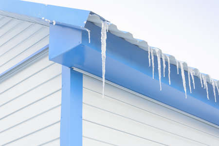Large icicles on roof of house in winter. Close-up, selective focus.の写真素材