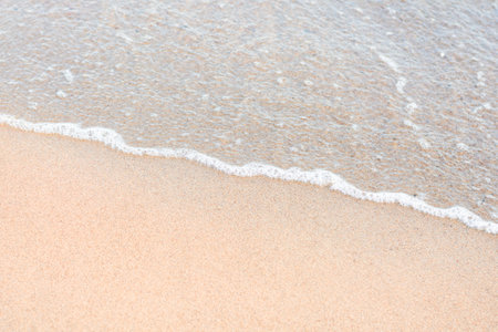 Soft sea wave running on sandy seashore. Selective focus, copy space.