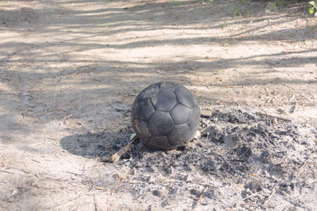 Old black soccer ball in the ashes of a campfire.の写真素材