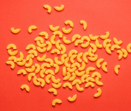 uncooked macaroni lies in different places on a red background