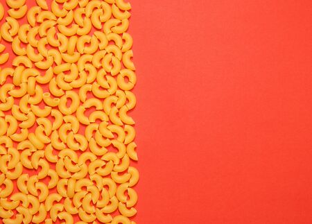 uncooked macaroni lies on one side on a red backgroundの写真素材