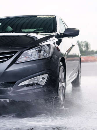 Detergent is washed off the front of a gray car with waterの写真素材
