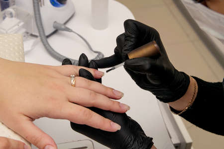 Close-up shot of nail polish by manicurist in black glovesの写真素材