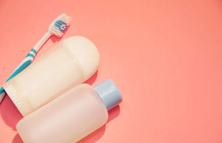 Toothbrush, deodorant and a jar of detergent lie on a pink background on the left side