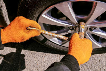 April 10, 2021 Russia. Tula. Parking lot at the Maxi Mall. Tire fitting the front wheel on the car unscrewing the wheel nut with a wheel wrenchのeditorial素材