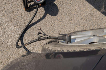 Pumping up one flat car tire with foot