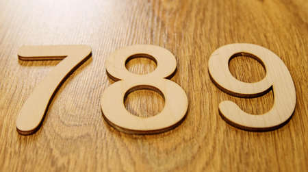 Flatley, side view of large wooden numbers seven, eight and nine lying in order on a wooden...