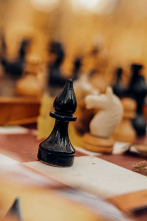 Chessboard in autumn yellow dry leaves with bishop close-up on blurred background restの写真素材