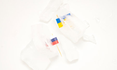 The split of two friendly countries. Two flags frozen in ice flags of Russia and Ukraine on a white...