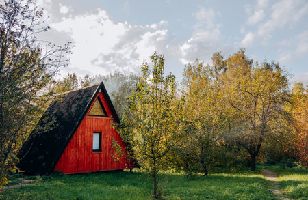 Autumn landscape of a red house near trees on a sunny dayの写真素材