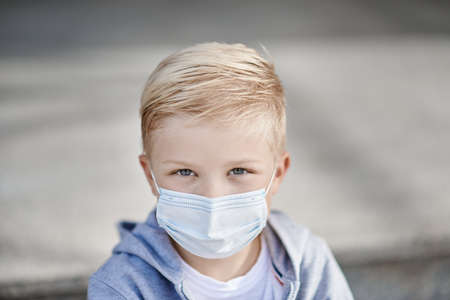Child with face mask looking at usの写真素材