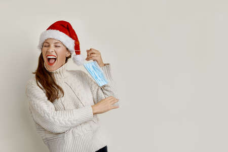 Woman wearing a Santa hat removing the protective mask