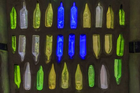 Wall with a green, yellow, white and blue glass bottleの写真素材