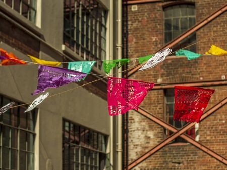 Colourful Mexican paper flags between buildingsの写真素材