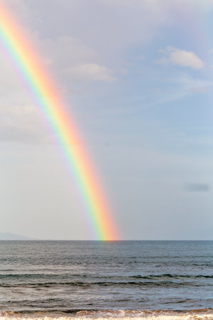 A rainbow on blue sky over endless waterの写真素材