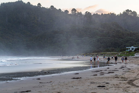 Whangamata, New Zealand - December 28, 2022: People enjoying a sunset walk in Whangamata beach, New Zealandのeditorial素材