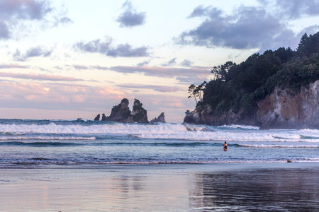 Whangamata, New Zealand - December 28, 2022: Woman enjoying a sunset swim in Whangamata beach, New Zealandのeditorial素材