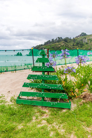 Christmas tree, crafted with creativity from pallets, stands proudly in a backyard garden overlooking the seaの写真素材
