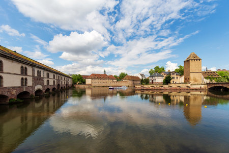 Strasbourg, France - May 13, 2024: Scenic view of Barrage Vauban and towers in Strasbourg with a canal boat cruising through the historic waterwaysのeditorial素材