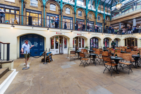 London, UK - May 16, 2024: A bustling indoor cafe scene at the Apple Market in Covent Garden, London, featuring a live singer and patrons enjoying the vibrant atmosphereのeditorial素材