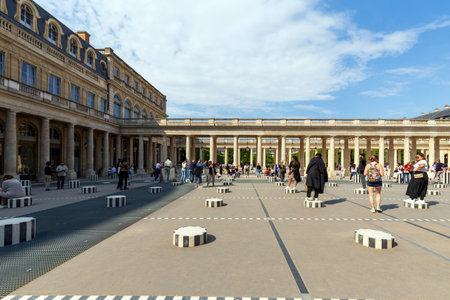 Paris, France - May 19, 2024: Tourists and locals alike explore the modern art installation in the courtyard of the historic Palais Royal in Paris, under a beautiful summer skyのeditorial素材