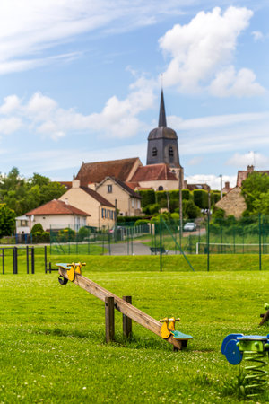 Nargis, France - May 26, 2024: Rural Village Playground with Seesaw and Church Spire, Nargis Franceのeditorial素材