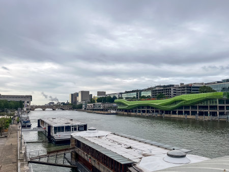 Paris, France - May 28, 2024: Contemporary riverside architecture and houseboats along the Seine River in Paris, France, under an overcast skyのeditorial素材